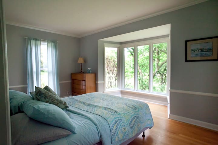 East wing suite bedroom with queen bed, midcentury modern furniture and sunrise views.