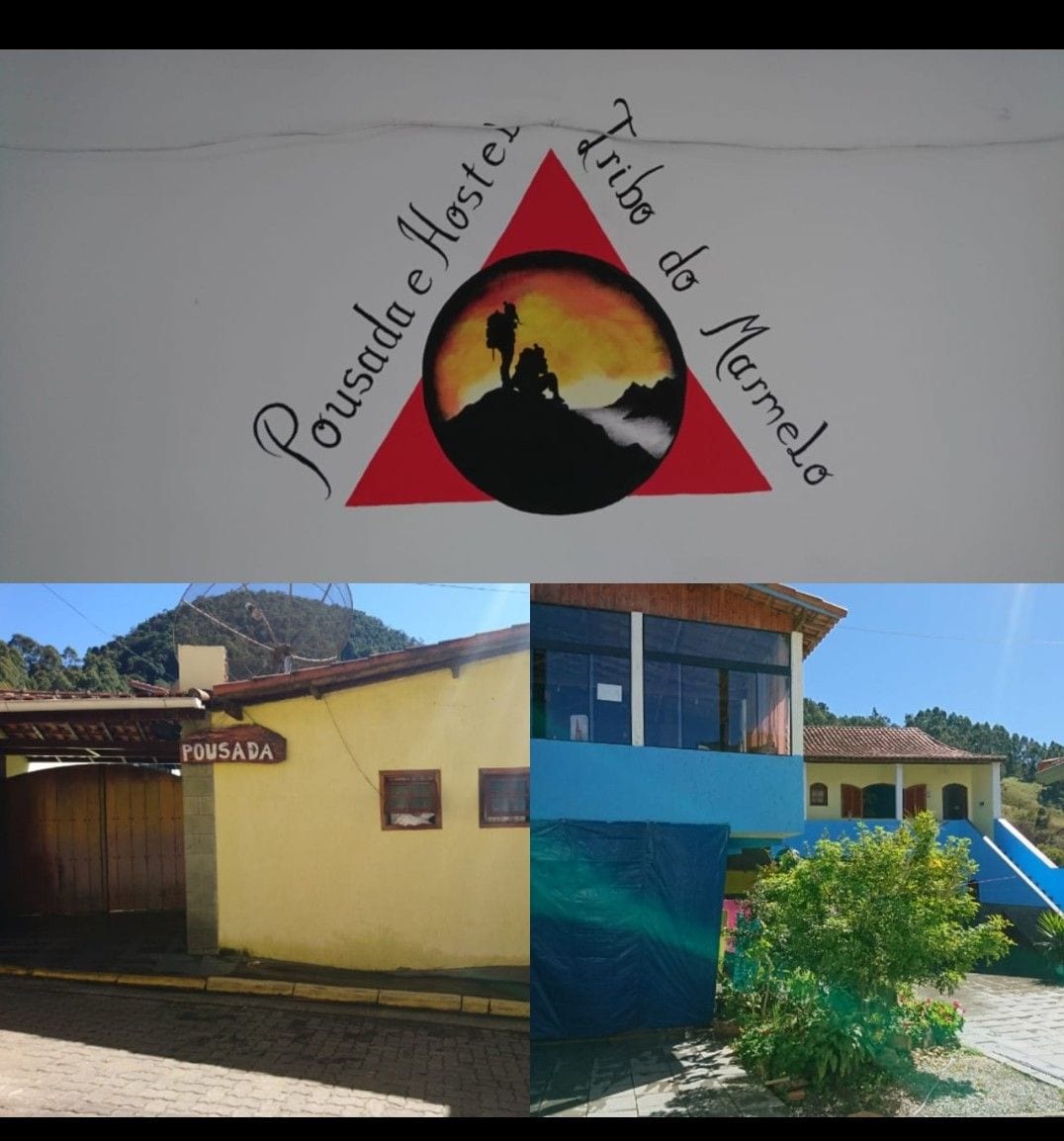 The image features a colorful mural displaying the name of the accommodation, with a mountain silhouette in the background. The exterior showcases a yellow building with a welcoming entrance and a blue awning. A vibrant green plant adds a natural touch to the setting.