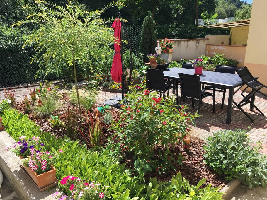 Jardin privatif orienté plein sud au calme avec table , chaises et parasol et sa piscine .