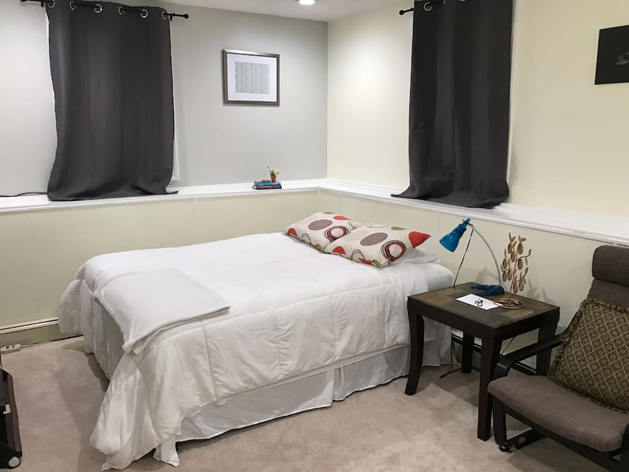 Queen bed with side table and chair.