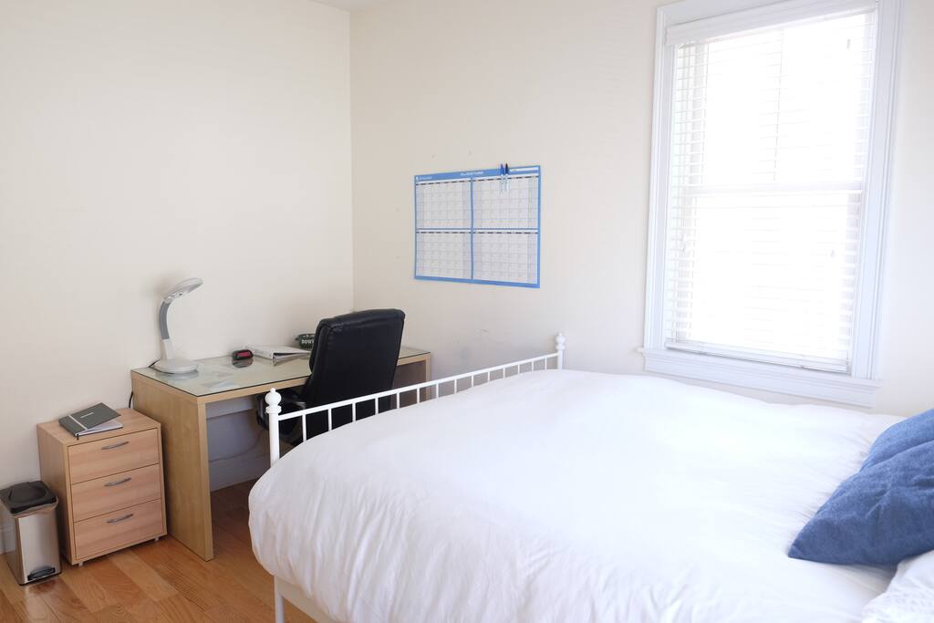 Well lit bedroom with queen bed and calendar for use. Air mattress (twin XL) to set up on request