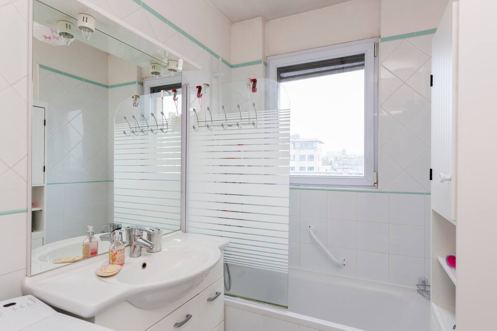Salle de bains lumineuse avec baignoire et pare douche