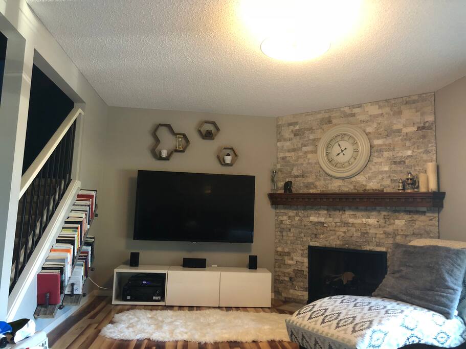 Living room with 65” TV, cable, and a wood burning fireplace