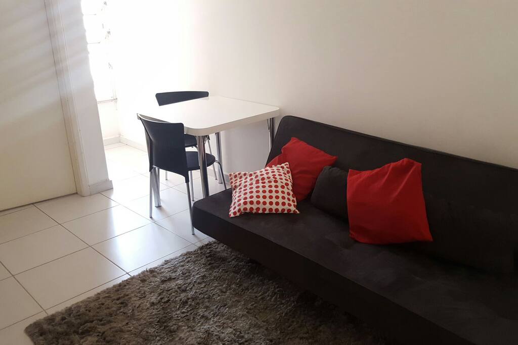 sala clara, com sofá-cama e mesa para 2