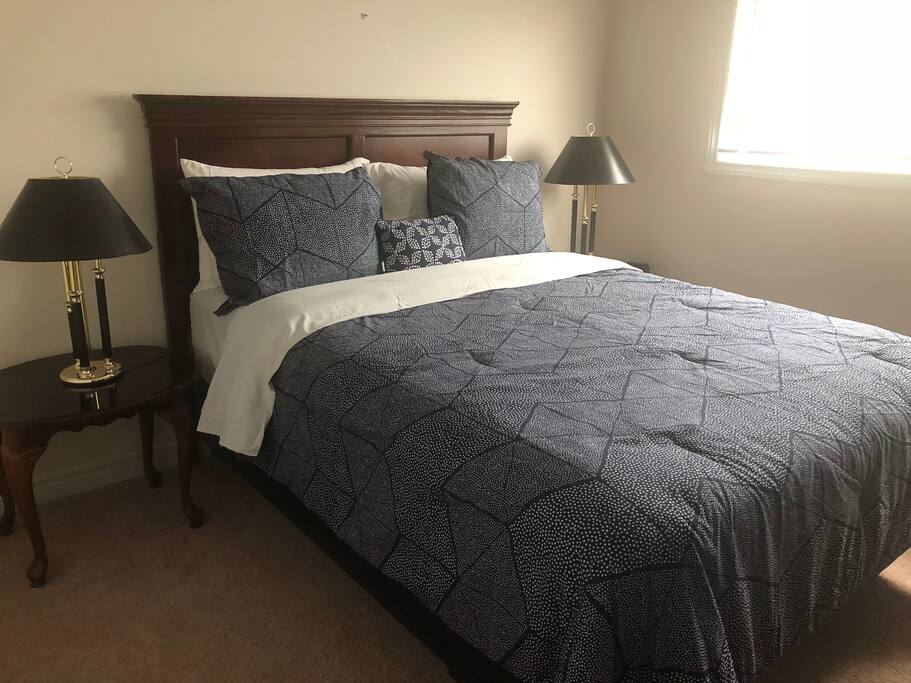 Queen size bed with small fridge on one side