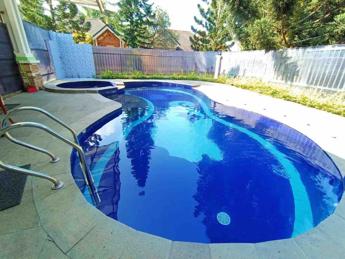 A private swimming pool is showcased, featuring a kidney-shaped design with clear blue water. Surrounding greenery adds a natural touch, while terrace tiles provide a smooth surface. Steps are visible leading into the pool, enhancing accessibility to the refreshing water.