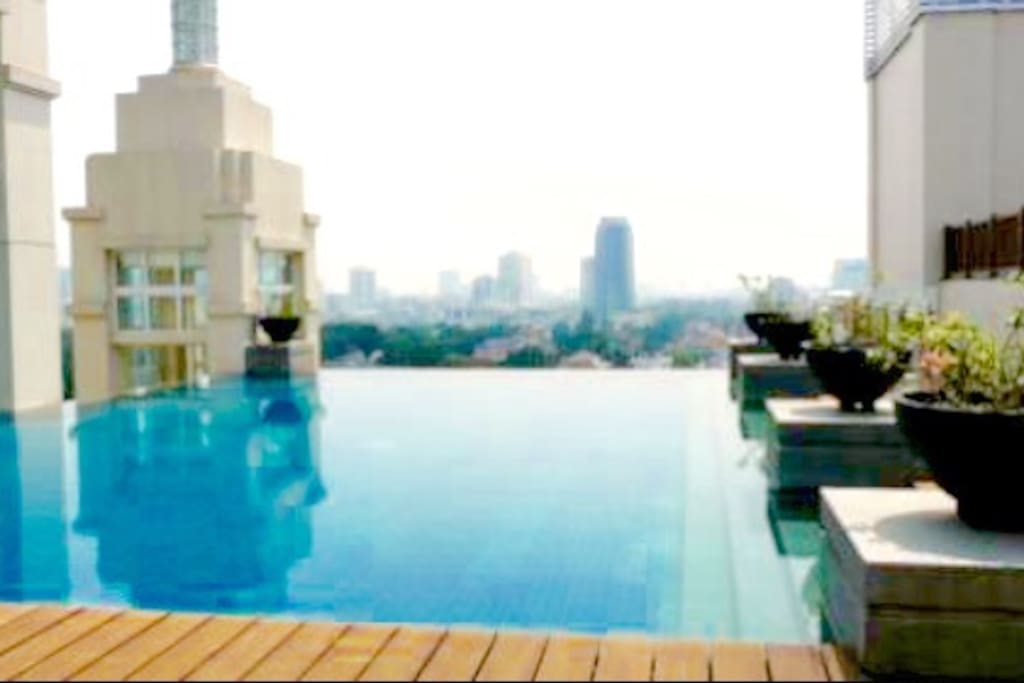 Outdoor rooftop infinity pool at noon with clear 360degrees view of Jakarta