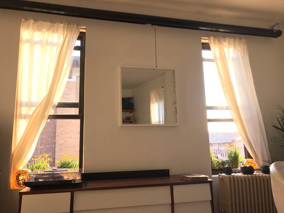 Four large sunny windows facing a historical church on a quiet residential street.