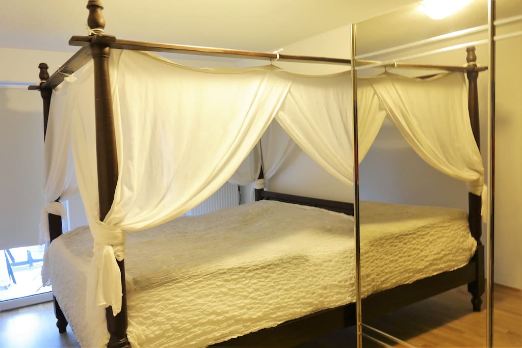 Schlafzimmer mit Himmelbett und einem Balkon
