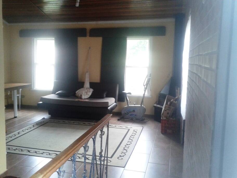 Escritório conjugado com mesa, sofá cama, rede e lareira