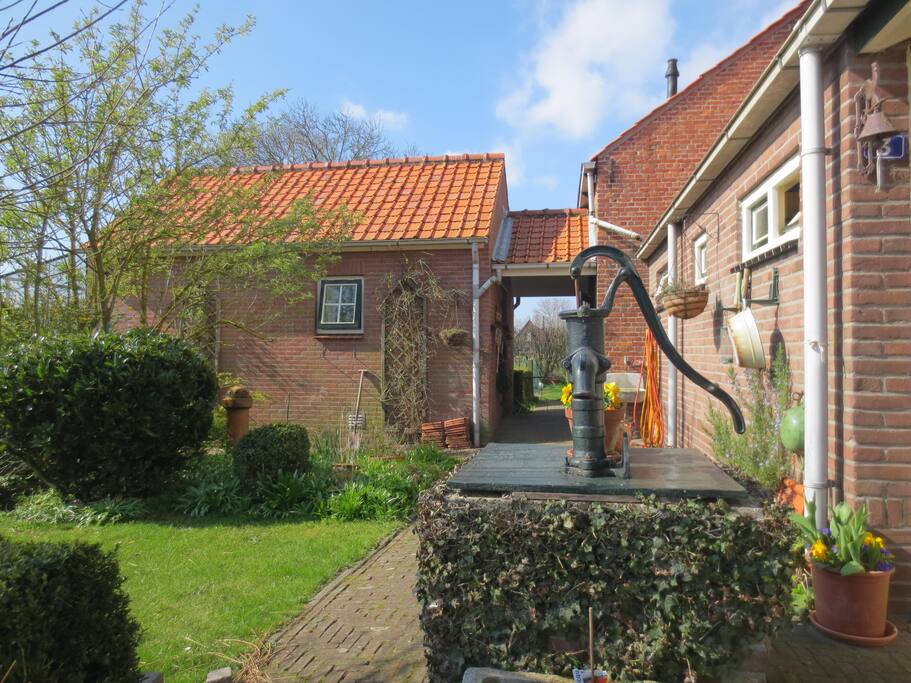 Links achter de waterput het logeerhuisje