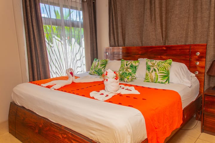 Მთავარი საძინებელი კომფორტული 193 × 203 სმ ზომის საწოლითა და უსაფრთხოების ყუთით, ტელევიზორით და A/C.