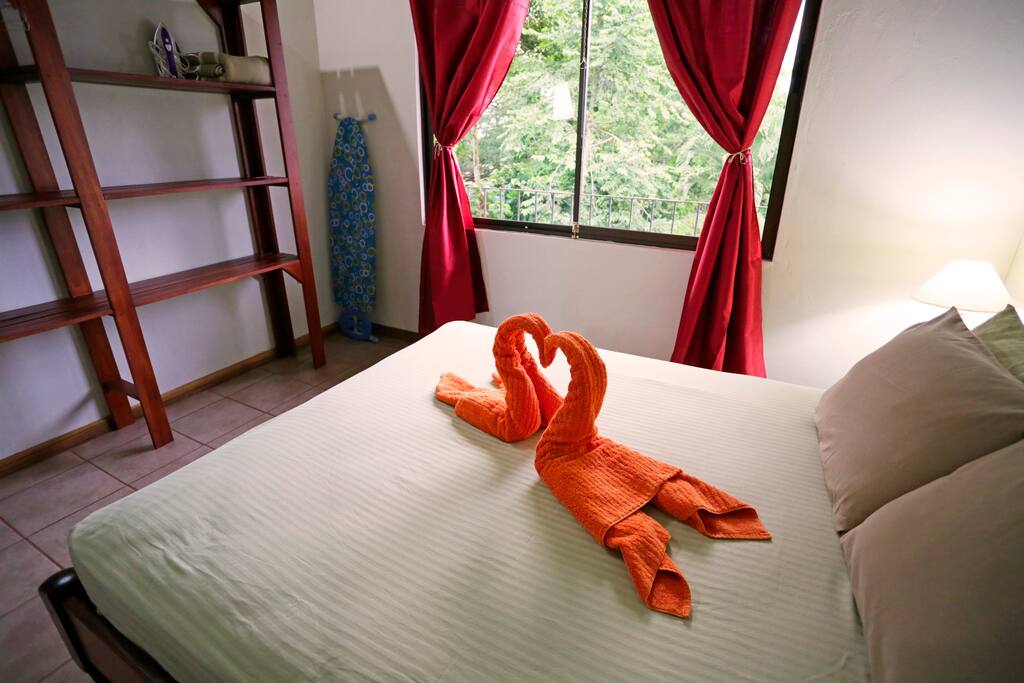 Master bedroom with queen size bed, colorful artwork and yard view.