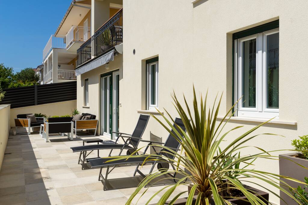 Private 46 m² terrace in front of the apartment with 2 sunbeds, three-seater, 2 armchairs and a table