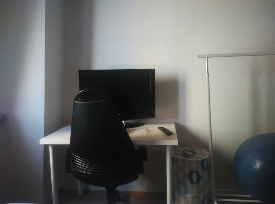 Office chair, desk, and TV in bedroom