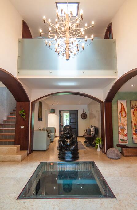 The grand entranceway opens up to an open-concept living space with a gorgeous chandelier and natural lighting.