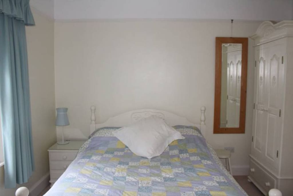 Bedroom with king size bed, desk, wardrobe, side cabinet, full length mirror radio and hair drier.