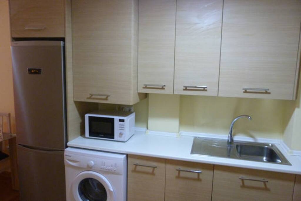 Cocina equipada con nevera-congelador combi alta gama, lavadora, microondas, horno, placa vitrocerámica, extractor de humos, tostador de pan, exprimidor de zumos, cafetera, batidora, menaje completo para cocinar, cubertería, y vajilla completa.