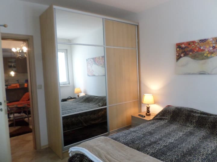 Bedroom with queen bed  and 2 cup boards (1 with mirror door ) with sliding doors, air con (hot & cold) , TV on the wall,  standing hanger and chair, 1 small  balcony
