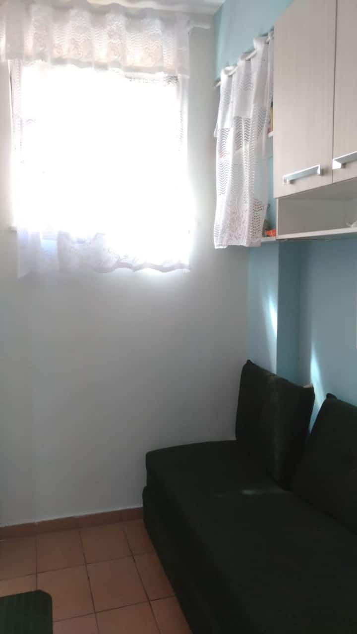 Малка стая (стая за прислугата) с вентилатор, двойно легло с възглавници, висящ гардероб, картина, дреболии, завеси, килер, прибори, килим...