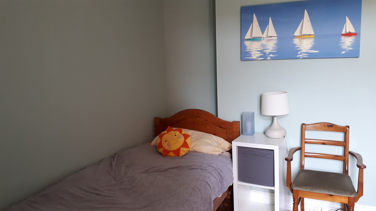 第四间卧室（楼下）配有单人床、通往后花园的露台门和办公桌。  