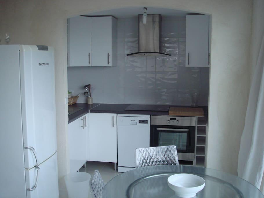 vue de la cuisine équipée avec plaque vitro, four, lave vaisselle, micro-onde et vaisselle, et casseroles
