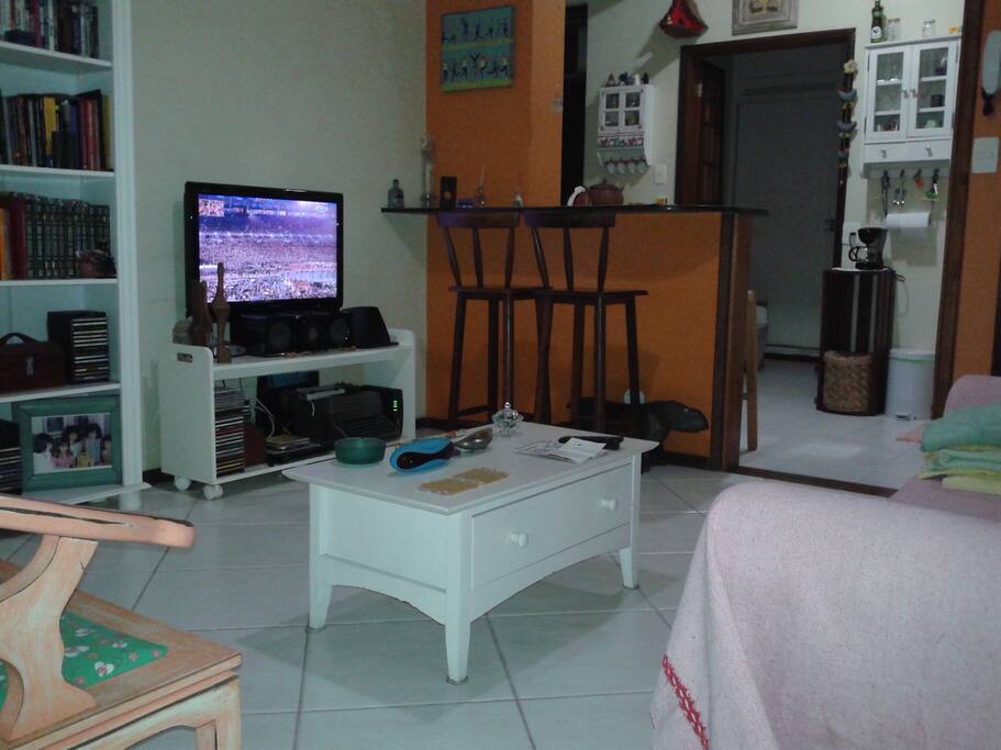 Sala com TV de tela plana e bancada da cozinha americana
