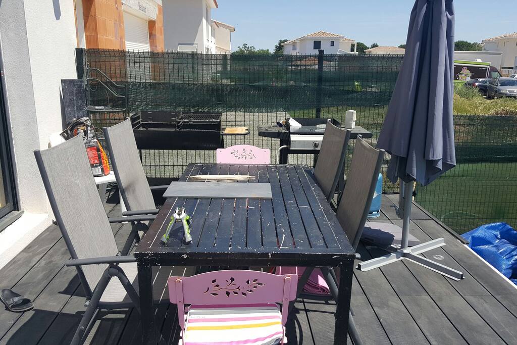 table avec chaises de jardin, barbecue à charbon de bois et plancha à gaz