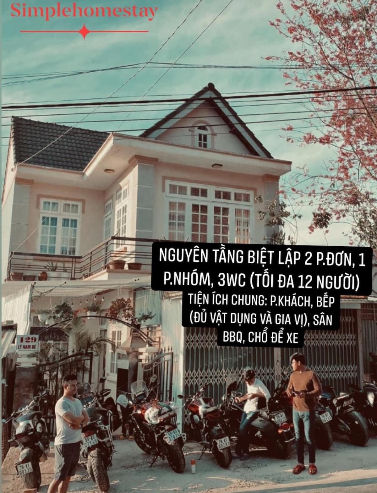A charming two-story villa is depicted, featuring a classic facade with multiple windows. Motorcycles are parked in front, illustrating convenient access. The property offers separate rooms and shared spaces accommodating groups of up to twelve guests, along with amenities for cooking and outdoor BBQ.