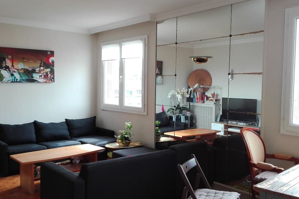 Salon avec 2 grands canapés méridiennes et une table basse. Vue sur tout Paris