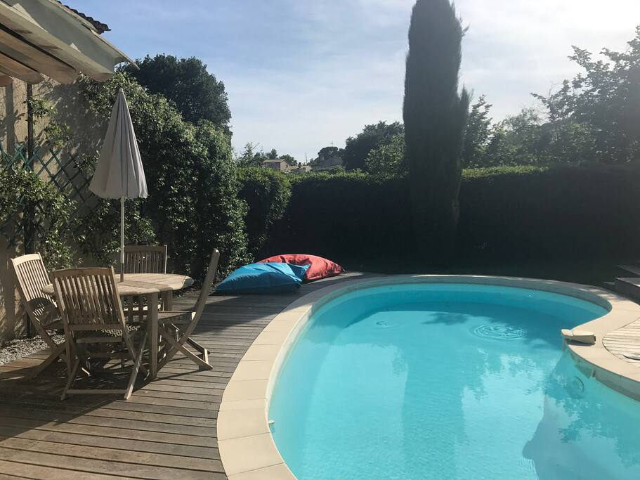 Coin cuisine d'été et poufs en bordure de la piscine.
