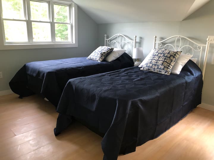 Spavaća soba u potkrovlju s dva odvojena XL kreveta s ekološkom i pravednom posteljinom.