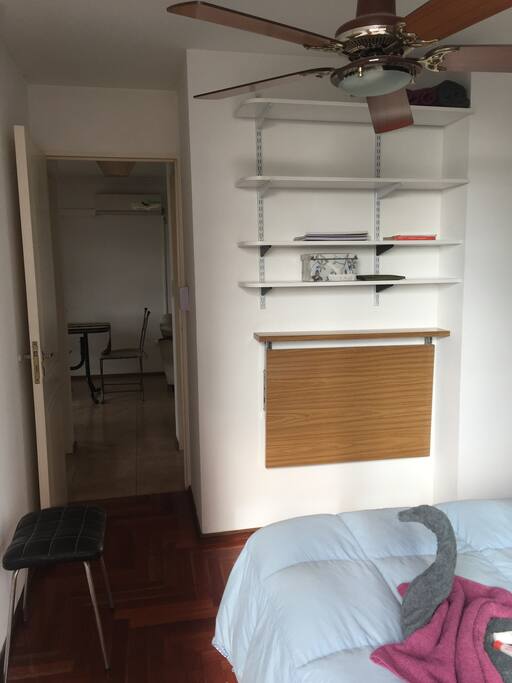 Entrada a la habitación desde living-comedor.
Estantería, mesa rebatible y ventilador de techo.
