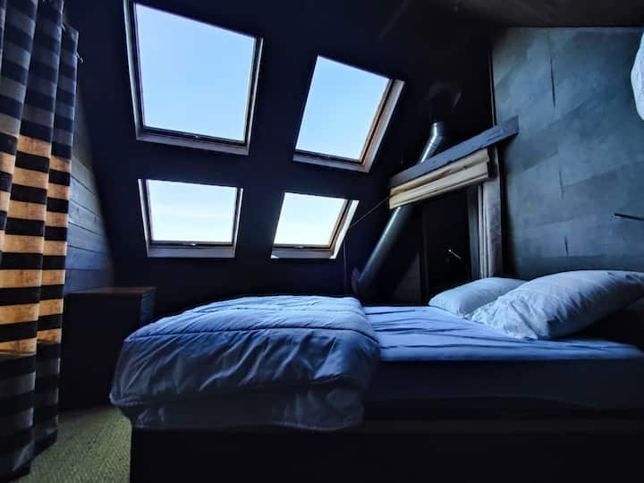 El dormitorio principal del ático con su techo de cristal con vistas a la noche estrellada