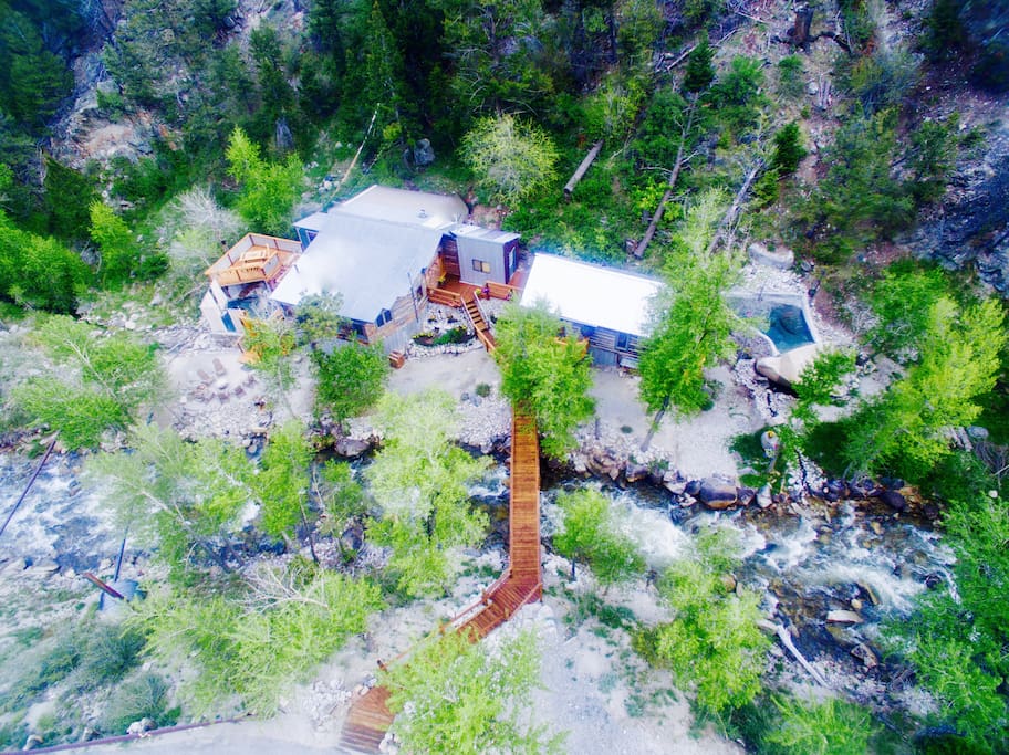 Aerial view of both cabins on the banks of Cottonwood Creek: Merrifield Cabin to the left of the bridge and Holloway Cabin to the right