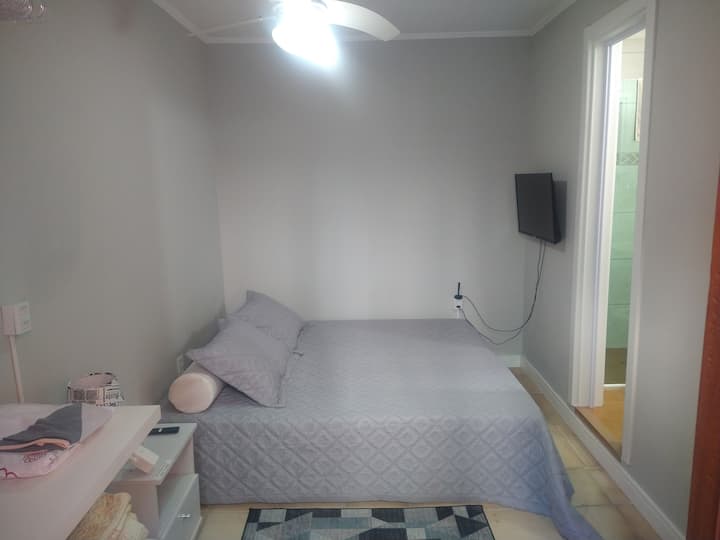 Suite avec lit double, télévision, ventilateur de plafond et placard ouvert.