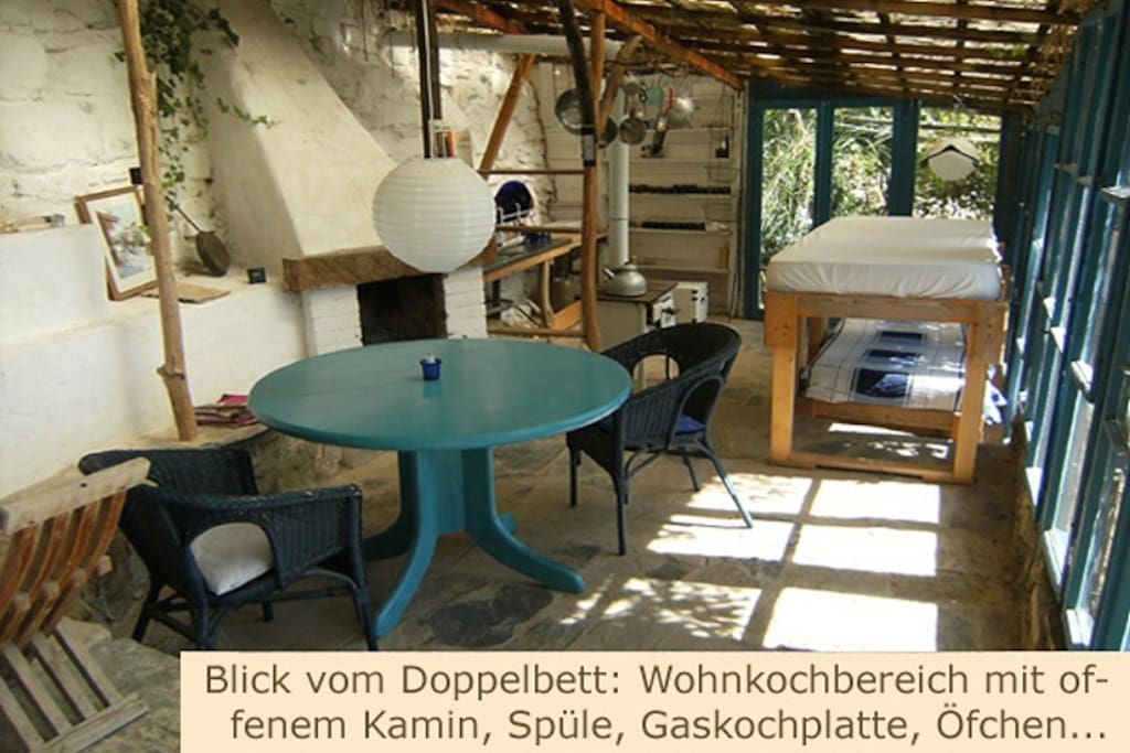 Blick vom Matrimonio-Doppelbett hinten: Wohn- und Kochbereich mit offenem Kamin, Spüle, Gaskochplatte, Öfchen, 2 Einzelbetten im versetzten Doppelstock.
