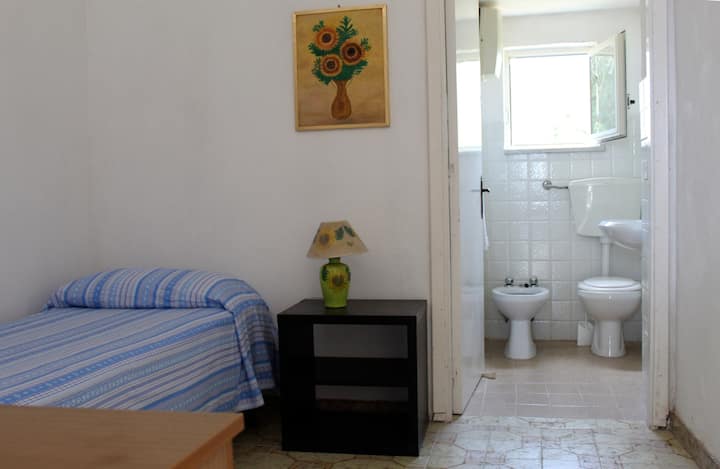 Slaapkamer met eenpersoonsbed.
Kleine badkamer op de achtergrond.