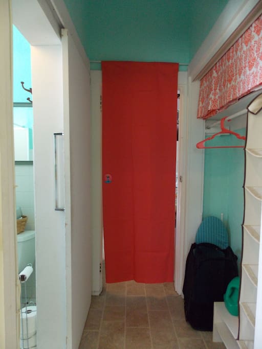 Your closet on the right, our shared bathroom on the left. The kitchen is beyond the red privacy curtain. There's a mat on the floor here to remind you to remove you shoes in the common areas.