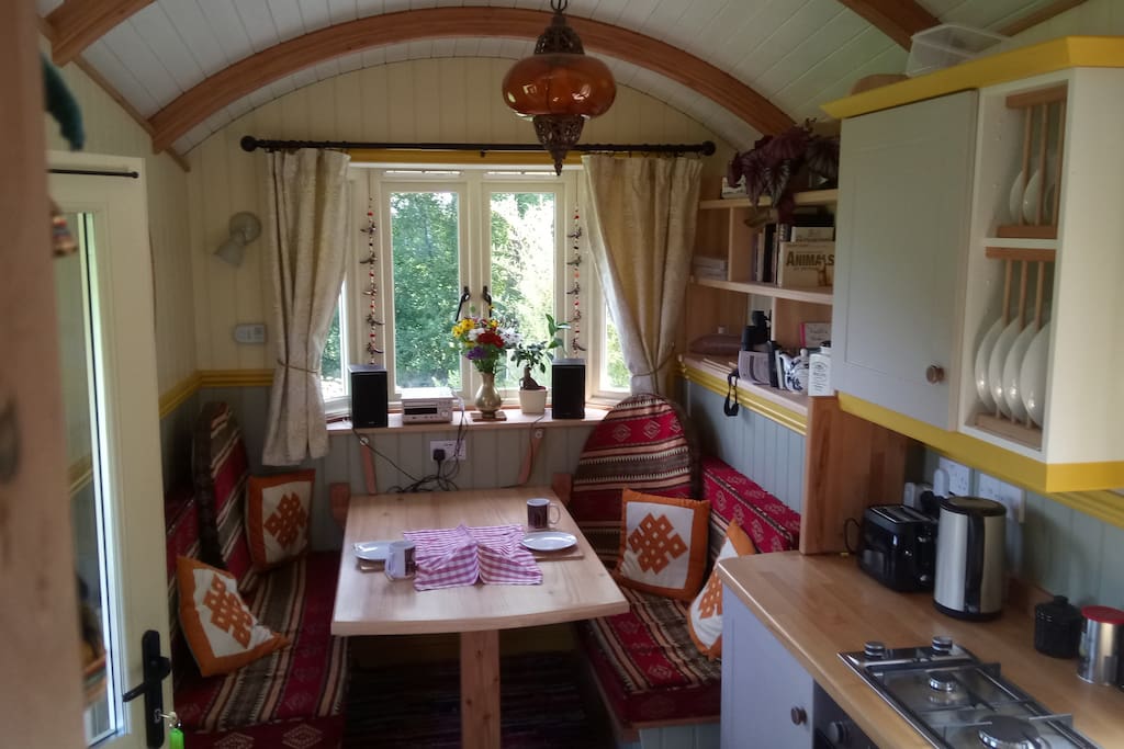The dining table and seating with the kitchen area in the foreground. The table and sitting area can be converted into a second double bed.