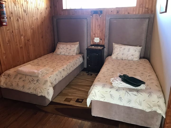 Chambre 4 - Plan ouvert - 2 lits simples, lampes de chevet et prises de courant.