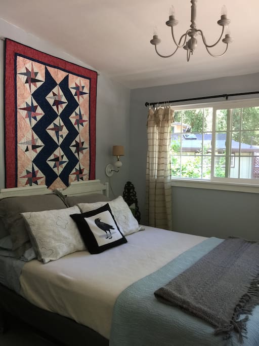 Bedroom with queen bed, extra pillows, and redwood forest views.