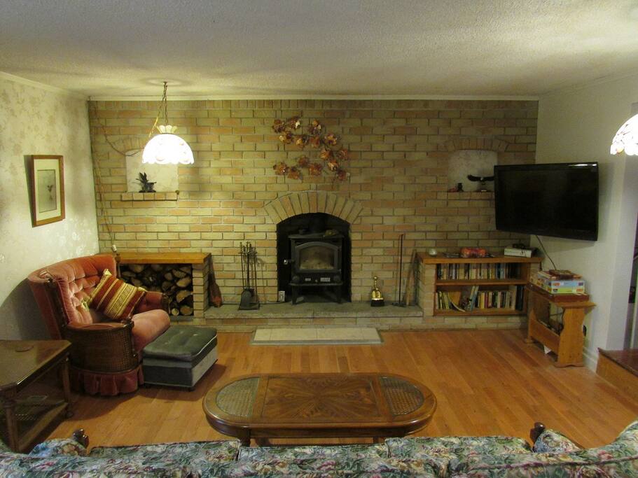 Large living room with pull out couch, flatscreen tv and wood burning fireplace. Also accesses large deck with BBQ.