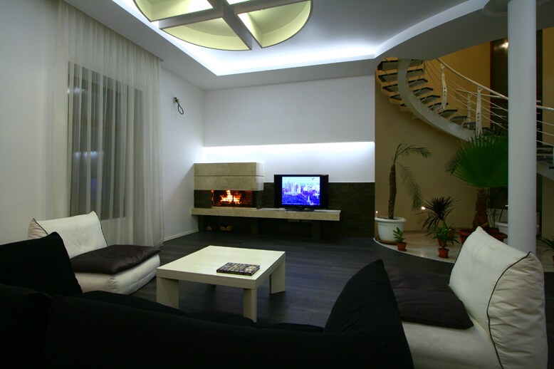 An open living area features a sleek coffee table at the center, surrounded by comfortable seating. A modern television is mounted on the wall, above a subtle fireplace that adds warmth to the ambiance. Soft lighting enhances the contemporary design elements.