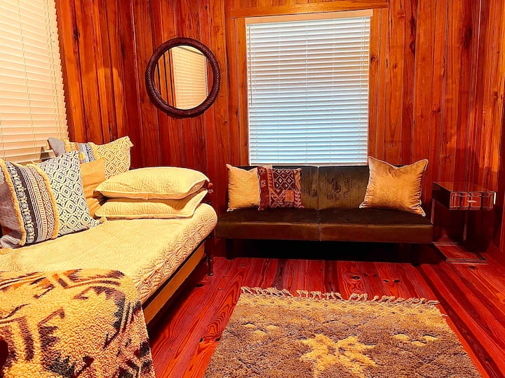 Útulná posteľ s prikrývkami a vankúšmi z Pendletonu. Sametový strieborný futón na spanie pre ďalšieho hosťa alebo len na oddych. Zrkadlové odkladacie stoly, výhľad do záhrady z okien a dostatok priestoru v skrini (kde žijú vintage trojkolka + kukuričné dosky GA Bulldogs).