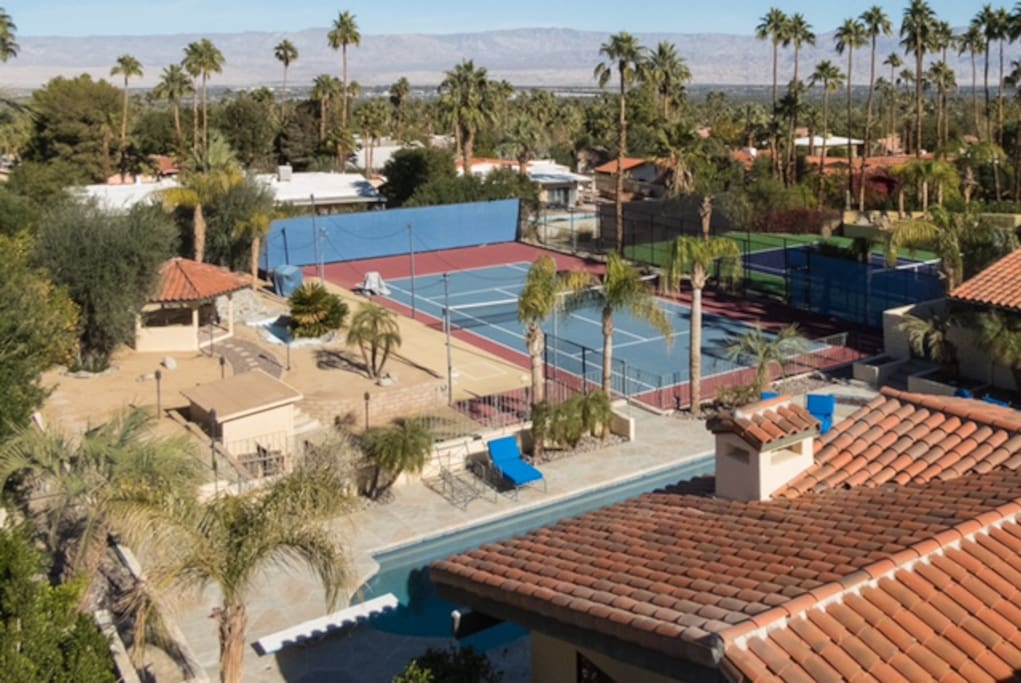 Outstretched beyond the patio is a full tennis court, pond, gazebo and fruit trees.