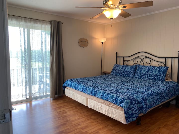 Chambre avec lit King Size et porte coulissante sur la terrasse arrière.
