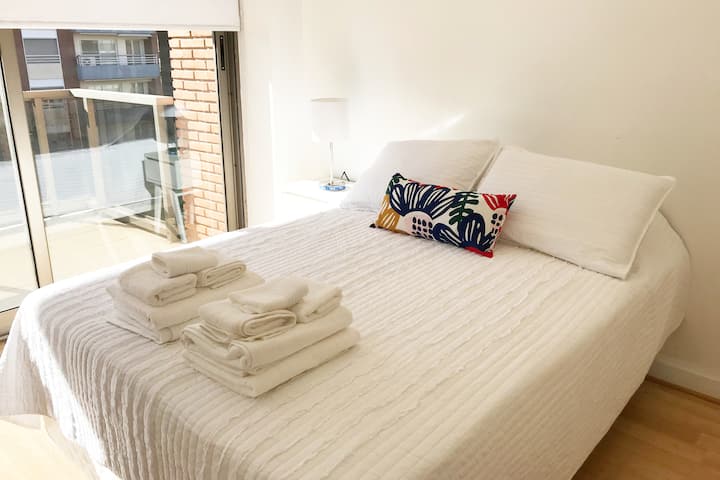 Habitación con cama matrimonial y acceso al balcón.
