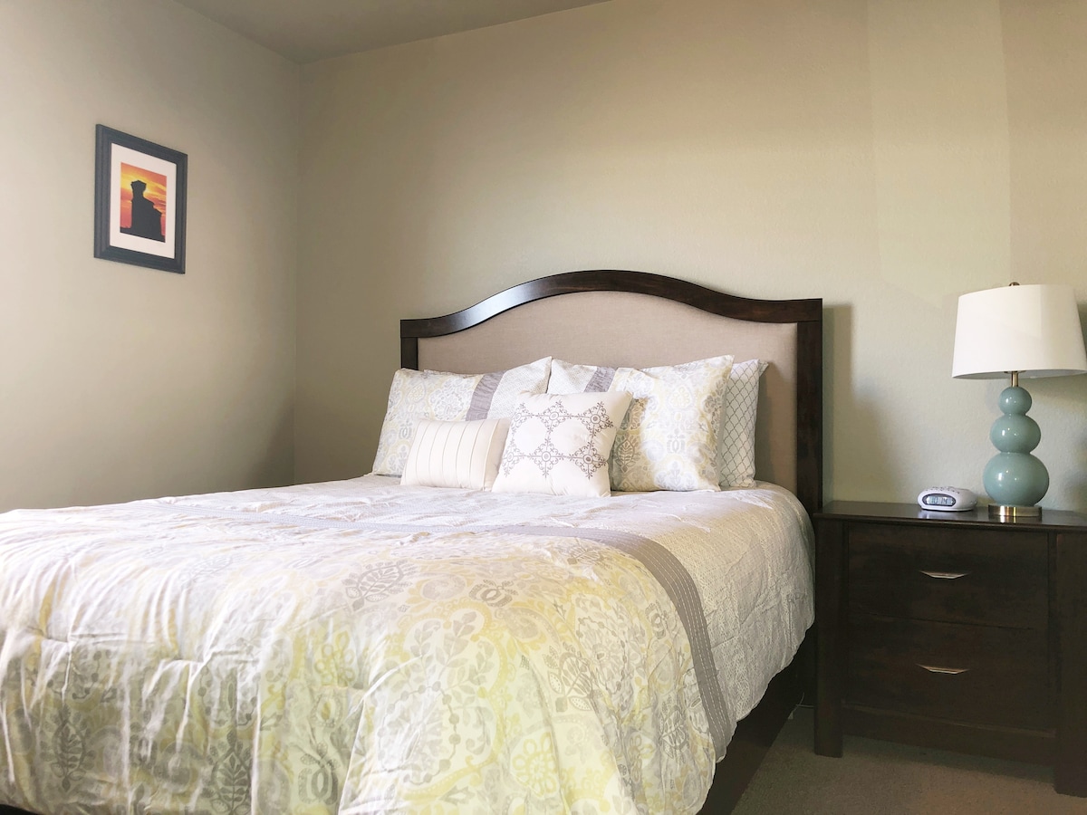 The Queen Suite has a ceiling fan with a queen size firm mattress, nightstand, alarm clock, lamp and wall mirror.