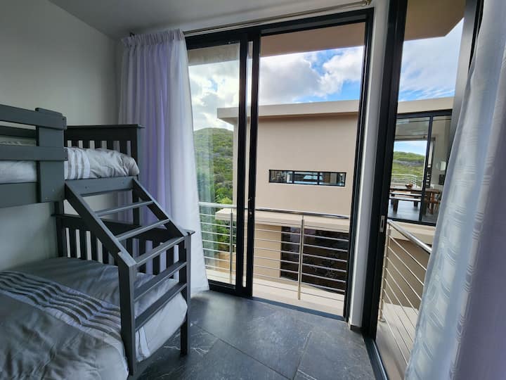 Dormitorio de invitados con cama de tres literas (doble e individual) con vistas al patio interior y a la montaña más allá.